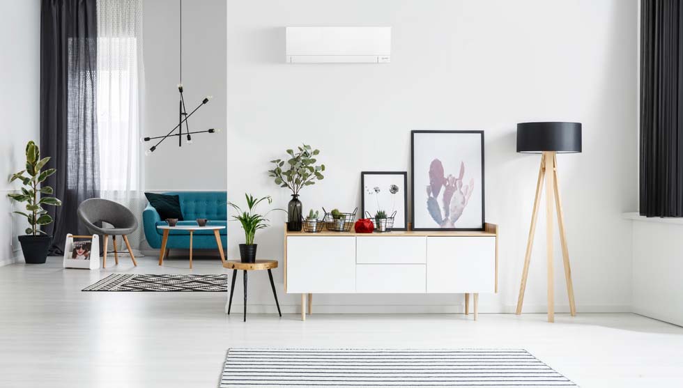 Grand salon blanc avec canapé bleu au fond et un bloc climatiseur sur le mur devant