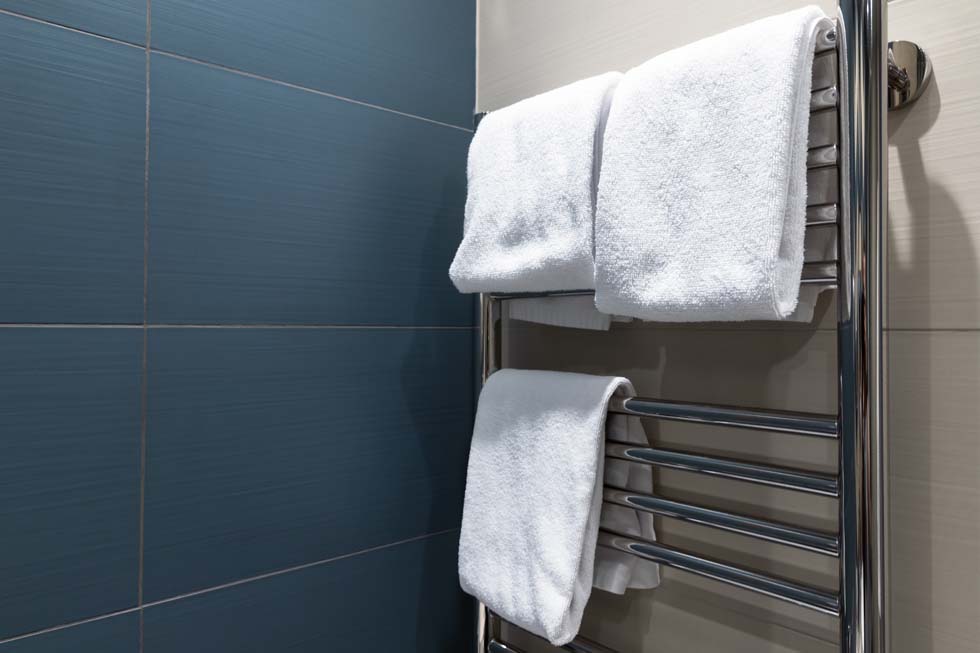 Les serviettes blanches sont séchées sur un sèche-serviettes dans la salle de bain