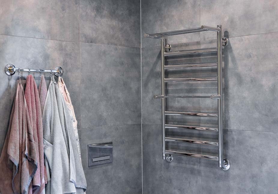 Sèche-serviettes et radiateur nouvellement installés, alimentés par une pompe à chaleur nouvelle génération, dans une salle de bains récemment aménagée d'une maison témoin. Une partie de la baignoire est visible en bas à droite, ainsi qu'un canard en plastique.