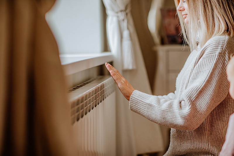 Une femme devant un radiateur